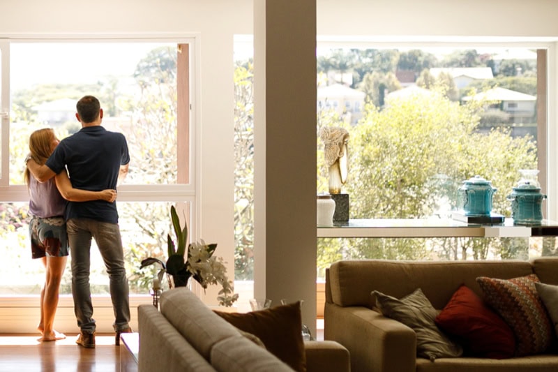 What’s That Smell Coming From My AC at Startup? Photo of a couple admiring the view from their living room window.